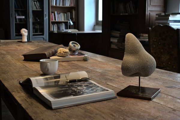 sculpture d'un nez en béton gris sur un socle en acier sur un bureau