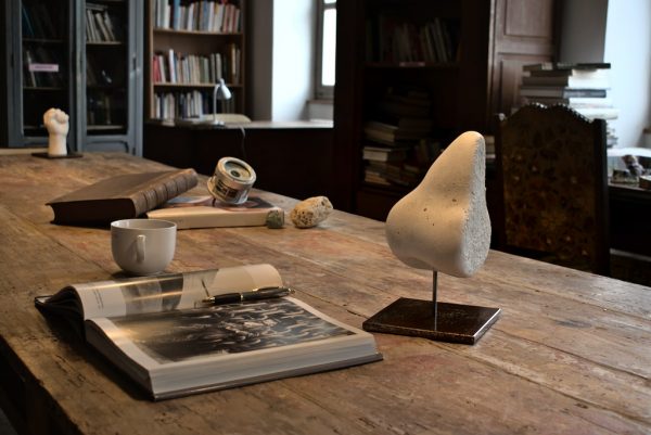 sculpture d'un nez en béton blanc sur un socle en acier sur un bureau.