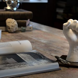 sculpture d'une main en plâtre blanc et son socle en acier posée sur une table